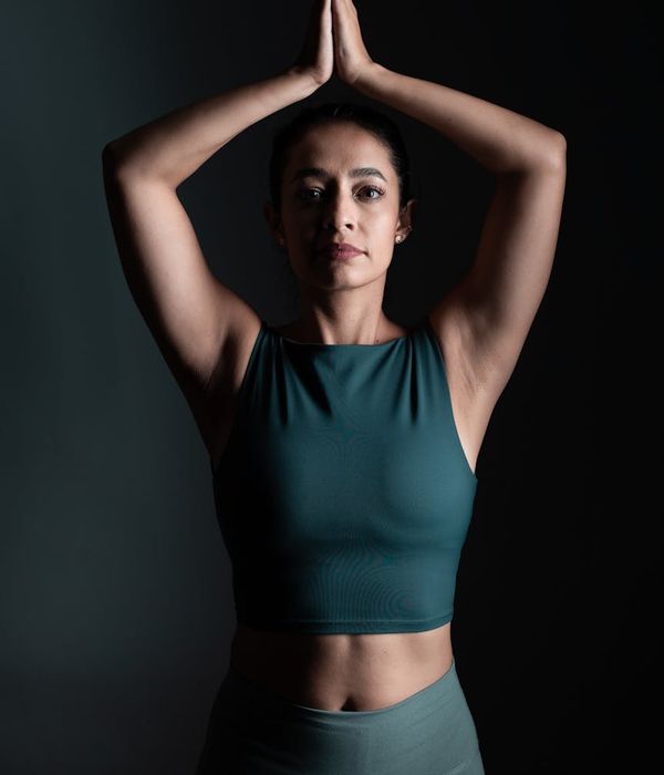 Woman in a peaceful yoga pose against a dark background with emerald light.